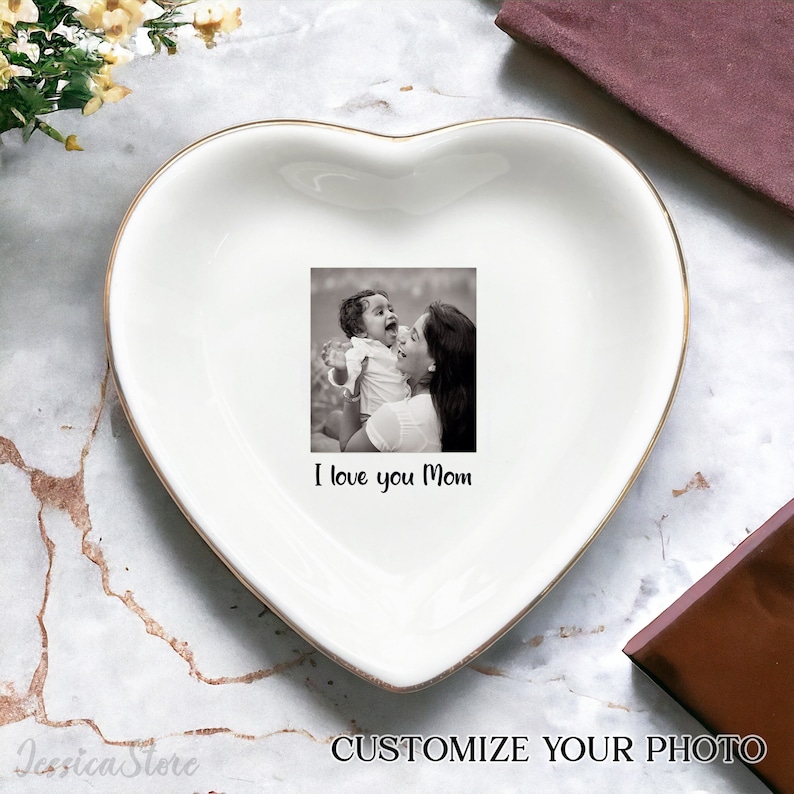 Puede incluir: Plato de cer&aacute;mica blanco en forma de coraz&oacute;n con borde dorado. El plato presenta una foto en blanco y negro de una madre y un hijo con el texto "I love you Mom".