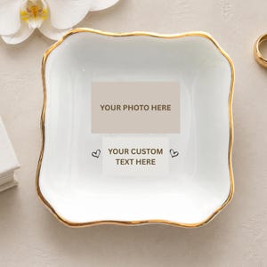 May include: A square white ceramic trinket dish with a scalloped edge and a gold-painted rim. The center features a rectangular placeholder with the text YOUR PHOTO HERE above a smaller box with the text YOUR CUSTOM TEXT HERE and two small hearts.