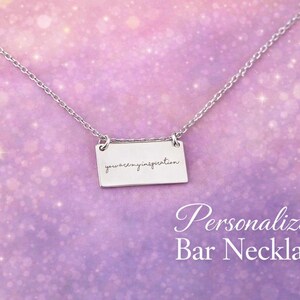 Peut inclure: Un collier barre argenté avec l'inscription "you are my inspiration" sur un pendentif rectangulaire. Le collier est présenté sur un fond violet doux avec le texte "Personalized Bar Necklace".