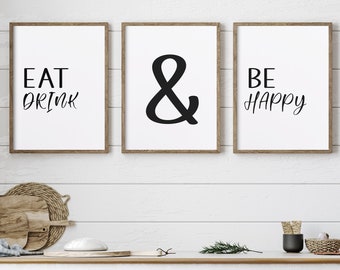 Peut inclure: Trois impressions encadrées avec du texte noir sur fond blanc. Les impressions indiquent "Eat Drink & Be Happy". Les impressions sont accrochées à un mur blanc en lambris au-dessus d'une armoire blanche à deux tiroirs.