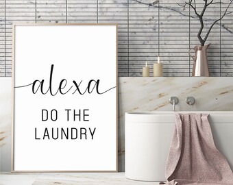 May include: A white framed print with black text that reads "alexa do the laundry" in a bathroom setting with a white bathtub and a marble countertop.