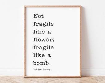 May include: A framed print with a black and white quote that reads "Not fragile like a flower, fragile like a bomb." The quote is attributed to Ruth Bader Ginsburg.