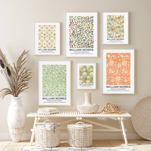 May include: A set of six framed prints featuring floral patterns by William Morris. The prints are displayed on a white wall with a white bench and wicker baskets in the foreground.