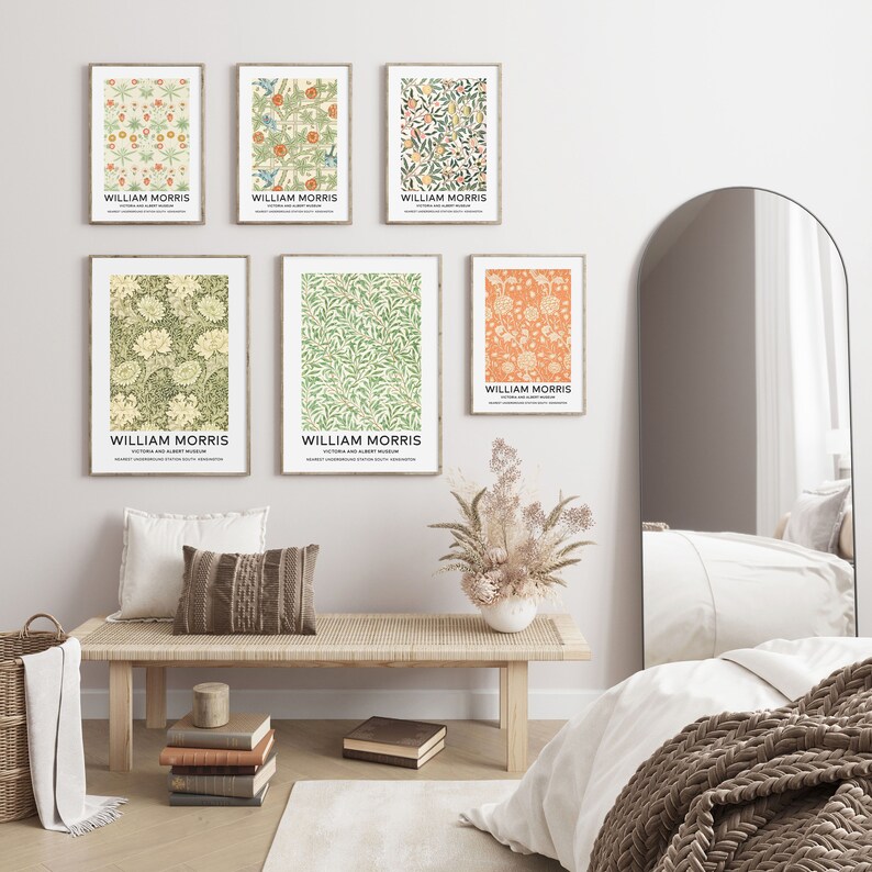May include: A set of six framed prints featuring floral patterns by William Morris. The prints are in a variety of colors, including green, orange, and yellow. The prints are hung on a white wall above a wooden bench.
