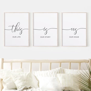 May include: Three framed prints with black calligraphy on a white background. The first print says "this our life", the second print says "is our story", and the third print says "us our home".