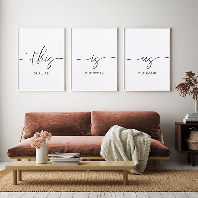May include: Three white framed prints with black calligraphy. The first print says "this our life", the second print says "is our story", and the third print says "us our home".