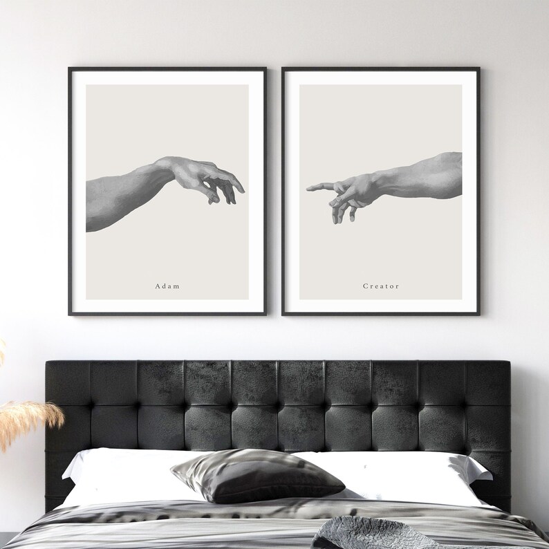 May include: Two black framed prints of the famous Michelangelo painting "The Creation of Adam". The prints are side-by-side and show the hands of God and Adam reaching towards each other. The text "Adam" is below the left hand and "Creator" is below the right hand.