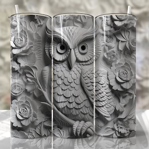 May include: A grey and white stainless steel tumbler with a 3D carved design of an owl and roses. The owl is in the centre of the design and the roses are surrounding it.
