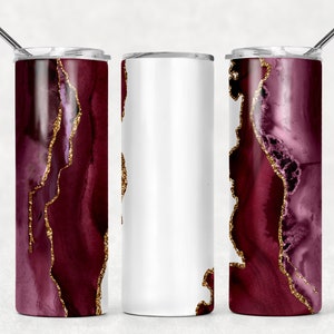 Puede incluir: Tres vasos de acero inoxidable con un diseño de ágata burdeos y dorado. El vaso de la izquierda y de la derecha tienen el diseño, mientras que el vaso del medio está en blanco.