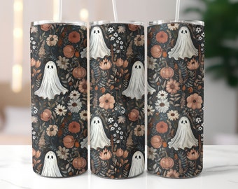 Könnte beinhalten: Drei Edelstahlbecher mit einem Halloween-Blumenmuster. Das Muster zeigt weiße Geister, Kürbisse und verschiedene Blumen in Orange-, Beige- und Weißtönen auf dunklem Hintergrund. Jeder Becher hat einen weißen Strohhalm.