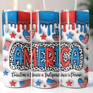 Op de afbeelding: Een witte tumbler met een rood, wit en blauw patriottisch ontwerp. De tumbler heeft het woord "AMERICA" in grote, vetgedrukte letters, samen met sterren, harten en vredestekens. De tekst "Freedom * Brave * Independence * Power" staat onderaan de tumbler.