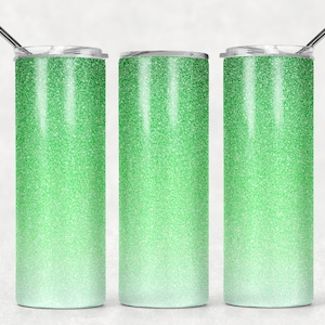 Könnte beinhalten: Drei Edelstahlbecher mit einem grünen Glitzer-Ombre-Design. Die Becher haben einen silbernen Deckel und einen Strohhalm.