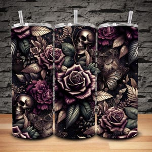 Puede incluir: Tres vasos aislados de acero inoxidable con tapas y pajitas. Los vasos presentan un diseño floral oscuro con rosas, mariposas, calaveras y follaje en tonos morados, dorados y negros. Los vasos son cilíndricos.