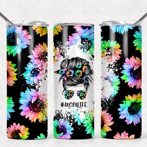 May include: A stainless steel tumbler with a black background and a colorful sunflower pattern. The tumbler has a white section with a drawing of a woman with a messy bun, sunglasses, and a butterfly in her hair. The text "#MOMLIFE" is printed below the drawing.