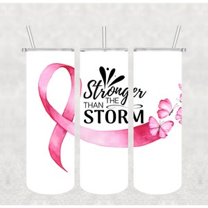 Pode incluir: Três copos brancos com desenhos de fita rosa, borboleta e aquarela. Os copos apresentam o texto "Stronger than the storm".