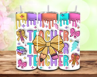May include: Three colorful 20 oz. tumblers with a teacher theme. Each tumbler features a white background with the word "TEACHER" in large letters, along with pencils, bows, and books. The tops of the tumblers have a dripping paint design.