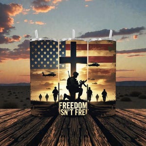 Puede incluir: Tres vasos de acero inoxidable con un diseño patriótico. El diseño presenta la bandera estadounidense, una cruz, siluetas de soldados, helicópteros y el texto "FREEDOM ISN'T FREE" sobre un fondo de puesta de sol. Cada vaso tiene una pajita transparente.