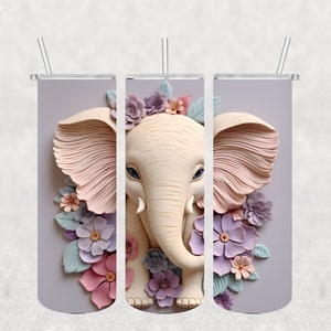 May include: A tumbler featuring a 3D illustration of an elephant with large ears and a trunk, surrounded by pastel-colored flowers and leaves. The elephant is cream-colored, and the flowers are pink, purple, and blue. The background is a light gray.