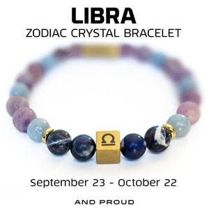May include: A Libra zodiac crystal bracelet featuring a mix of purple, blue, and gold beads. The bracelet includes a gold cube with the Libra symbol and is inscribed with the text "September 23 - October 22" and "AND PROUD".