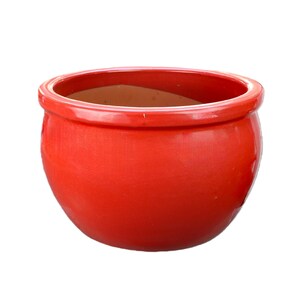Op de afbeelding: Een ronde, komvormige plantenbak met een glanzende, felrode buitenkant en een gladde, afgeronde rand. De binnenkant van de pot heeft een neutrale, ongeglazuurde beige kleur en is voorzien van een brede opening en een diepe, gebogen kom.