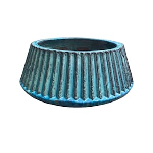 Puede incluir: Una maceta de cerámica turquesa con un exterior acanalado y texturizado. La maceta tiene una parte superior ancha y abierta y una base ligeramente ensanchada. El color es un verde azulado vibrante con acentos más oscuros en las ranuras.