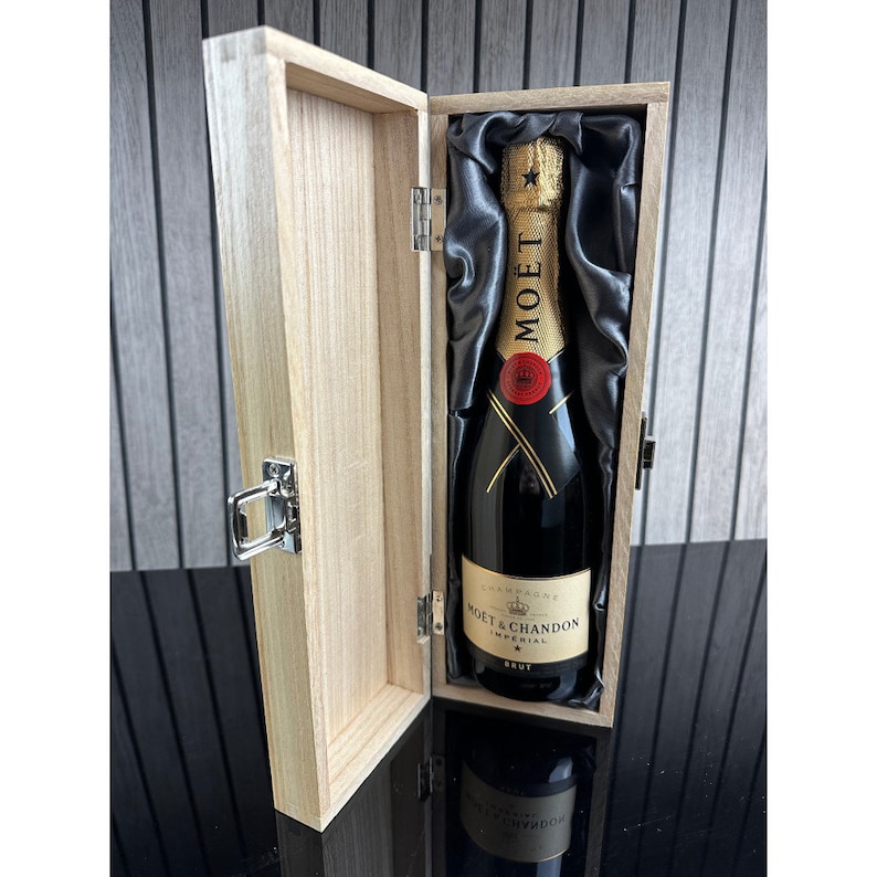 May include: A wooden box with a hinged lid, containing a bottle of Mo&euml;t & Chandon Imperial Brut champagne. The box is lined with black satin.