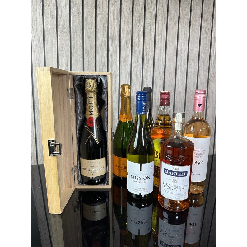 May include: A wooden gift box with a selection of bottles of wine and liquor. The box contains a bottle of Mo&euml;t & Chandon champagne, a bottle of Mission Hill wine, a bottle of Martell cognac, a bottle of red wine, and a bottle of ros&eacute; wine.