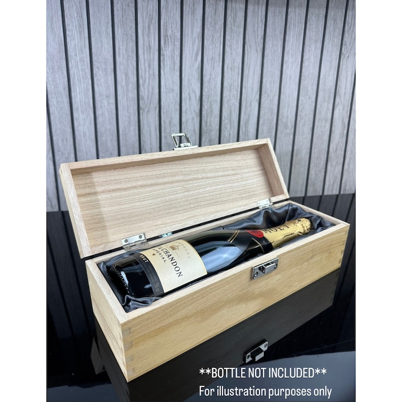 May include: A wooden box with a hinged lid and a satin lining. The box is designed to hold a bottle of champagne. The box is closed and a bottle of champagne is visible inside. **BOTTLE NOT INCLUDED** For illustration purposes only.