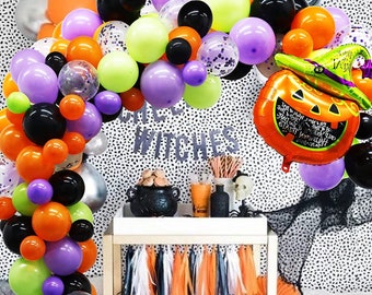 May include: A Halloween party decoration arch made of purple, orange, green, black, and clear balloons. The arch is decorated with confetti and a pumpkin balloon with a witch's hat. The text "Happy Halloween" is printed on the pumpkin balloon.