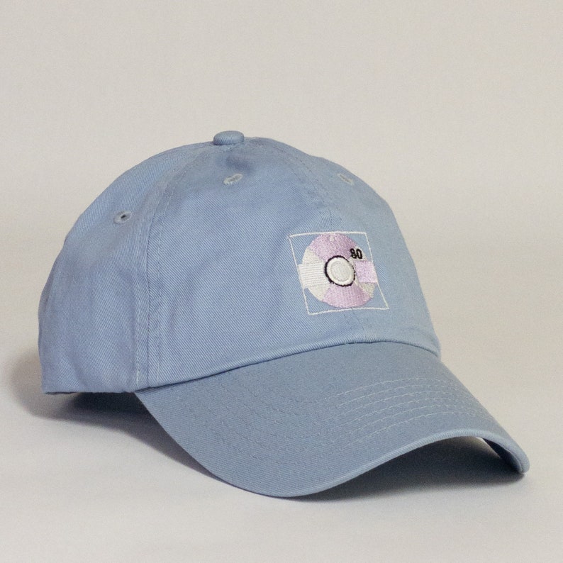 May include: A light blue baseball cap with an embroidered design of a compact disc with the number "80" on it.