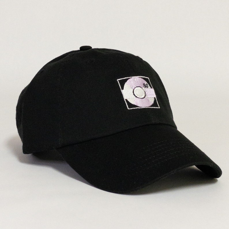 May include: Black baseball cap with a white embroidered design of a record with the number 80 on it.