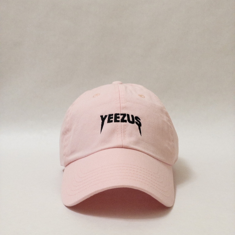 K&ouml;nnte beinhalten: Eine rosafarbene Baseballkappe mit einem schwarzen, gestickten "YEEZUS"-Logo.