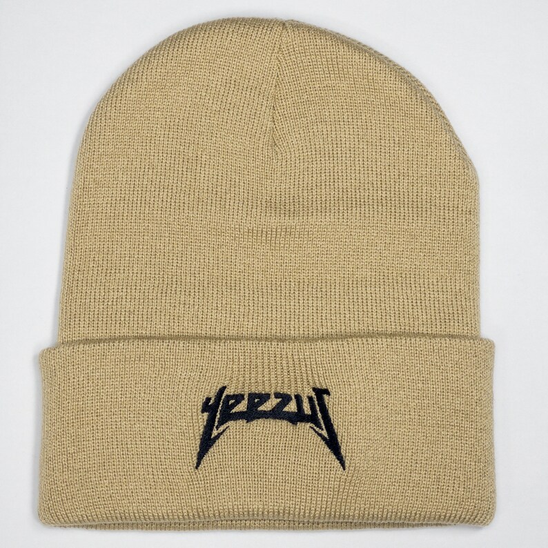 May include: A beige knitted beanie with a black embroidered "YEEZY" logo.