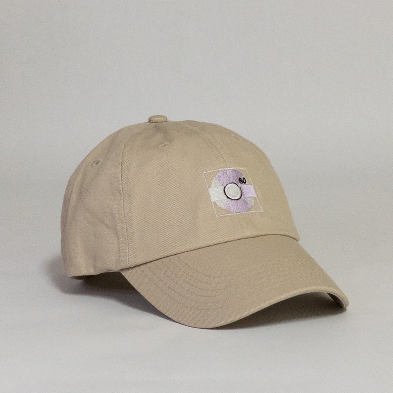 May include: A beige baseball cap with a purple and white embroidered patch of a record with the number 80 on it.