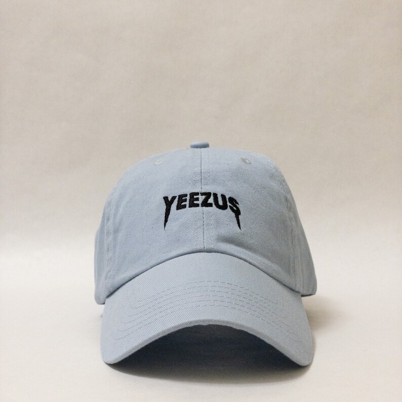K&ouml;nnte beinhalten: Eine hellblaue Baseballkappe mit dem Wort "YEEZUS" in Schwarz auf der Vorderseite gestickt.