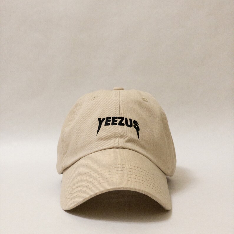 K&ouml;nnte beinhalten: Eine beige Baseballkappe mit einem schwarzen gestickten "YEEZUS"-Logo.