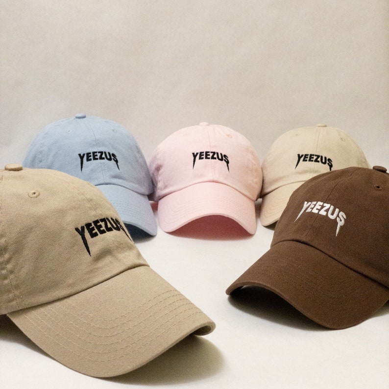 K&ouml;nnte beinhalten: F&uuml;nf Baseballkappen in verschiedenen Farben, darunter hellblau, rosa, beige, braun und braun. Jede Kappe tr&auml;gt den Schriftzug "YEEZUS" in schwarzer Stickerei auf der Vorderseite.