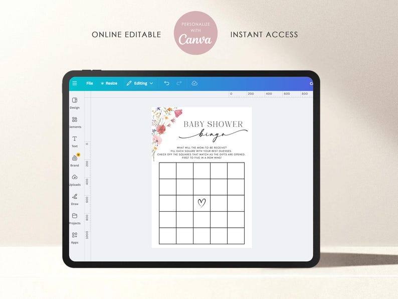 May include: A digital tablet displays a baby shower bingo card template. The card features a grid with a heart in the center, floral accents, and the text "BABY SHOWER bingo." Additional text reads "ONLINE EDITABLE" and "INSTANT ACCESS."