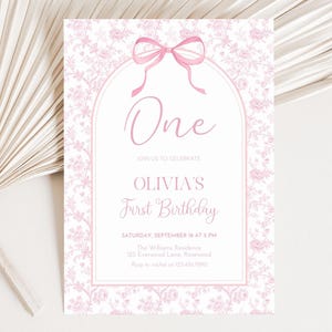 Puede incluir: Una invitación de primer cumpleaños con estampado floral rosa y blanco. La invitación presenta un lazo rosa y el texto "One" y "Olivia's First Birthday". La invitación también incluye la fecha, la hora y el lugar de la fiesta.