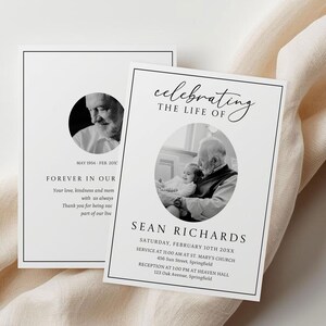 K&ouml;nnte beinhalten: Zwei wei&szlig;e Gedenkkarten mit schwarzem Text und einem Schwarz-Wei&szlig;-Foto. Auf einer Karte steht "Forever in Our" und auf der anderen "Celebrating the Life of" mit dem Namen "Sean Richards" und Veranstaltungsdetails. Die Karten liegen auf einem cremefarbenen Stoff.