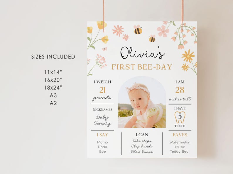 May include: A personalized 'First Bee-Day' sign featuring a baby's photo, floral and bee illustrations. The sign includes the baby's name, weight (21 pounds), height (28 inches), nicknames, and favorite things. Available in various sizes.