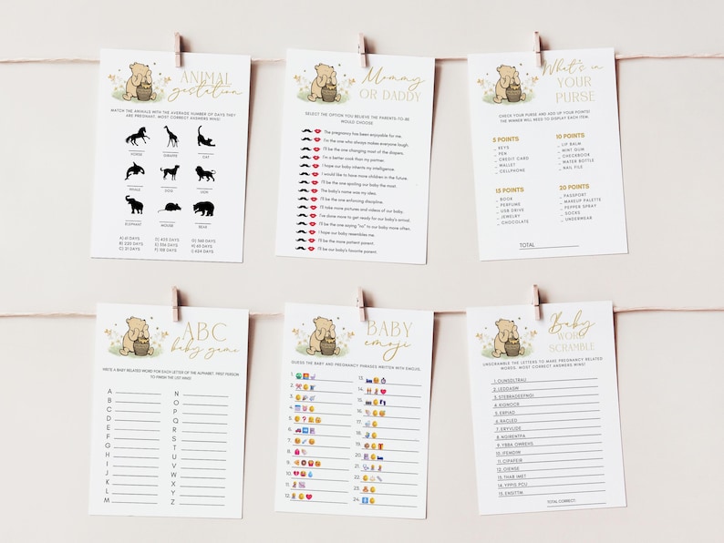 May include: Six baby shower game cards are displayed, each held by a wooden clip on a string. The cards feature a Winnie the Pooh theme with gold text and illustrations. Games include "Animal Gestation," "Mommy or Daddy," and "What's in Your Purse."