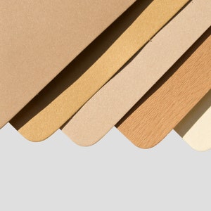 May include: Five different shades of brown paper samples arranged in a fan shape. The colors range from light beige to dark brown.