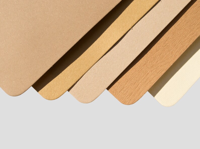 May include: Five different shades of brown paper samples arranged in a fan shape. The colors range from light beige to dark brown.