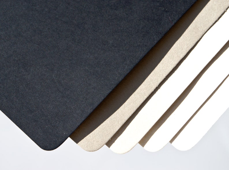 May include: A stack of different colored paper sheets, with the top sheet being black, the next sheet being a light brown, and the remaining sheets being white.