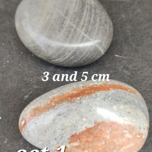 Puede incluir: Dos piedras pulidas, una gris con vetas, la otra gris con bandas rojas y blancas. El texto de la imagen dice "3 y 5 cm" y "set 1".
