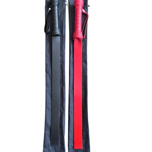 May include: Two leather paddles, one black and one red, with braided handles, are displayed in their black carrying cases.