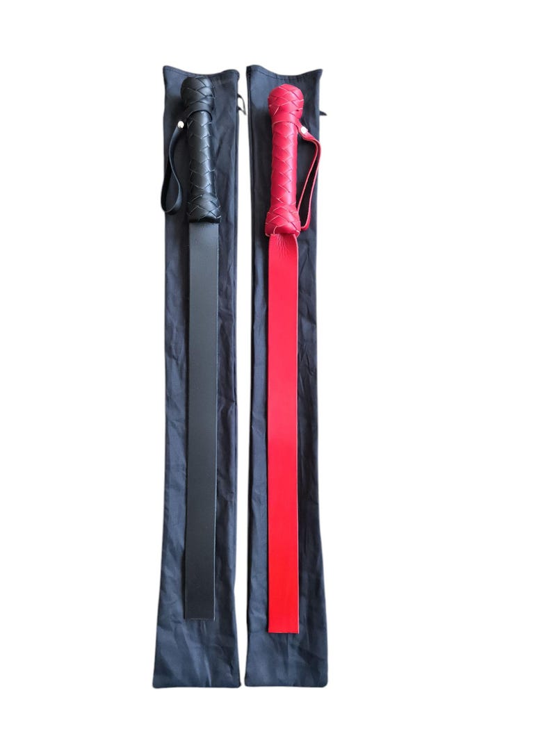 May include: Two leather paddles, one black and one red, with braided handles, are displayed in their black carrying cases.