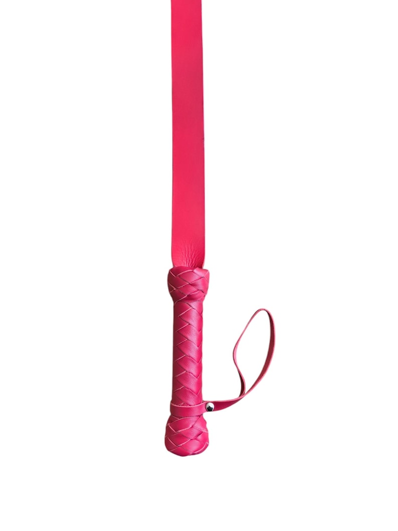 May include: A pink leather whip with a braided handle and a strap.