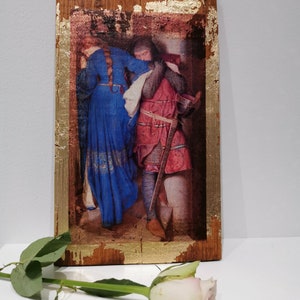 Op de afbeelding: Een ingelijst schilderij van een man en een vrouw in middeleeuwse kleding. De man draagt ​​een harnas en de vrouw draagt ​​een blauwe jurk. Het schilderij is in een houten lijst met gouden bladaccenten.